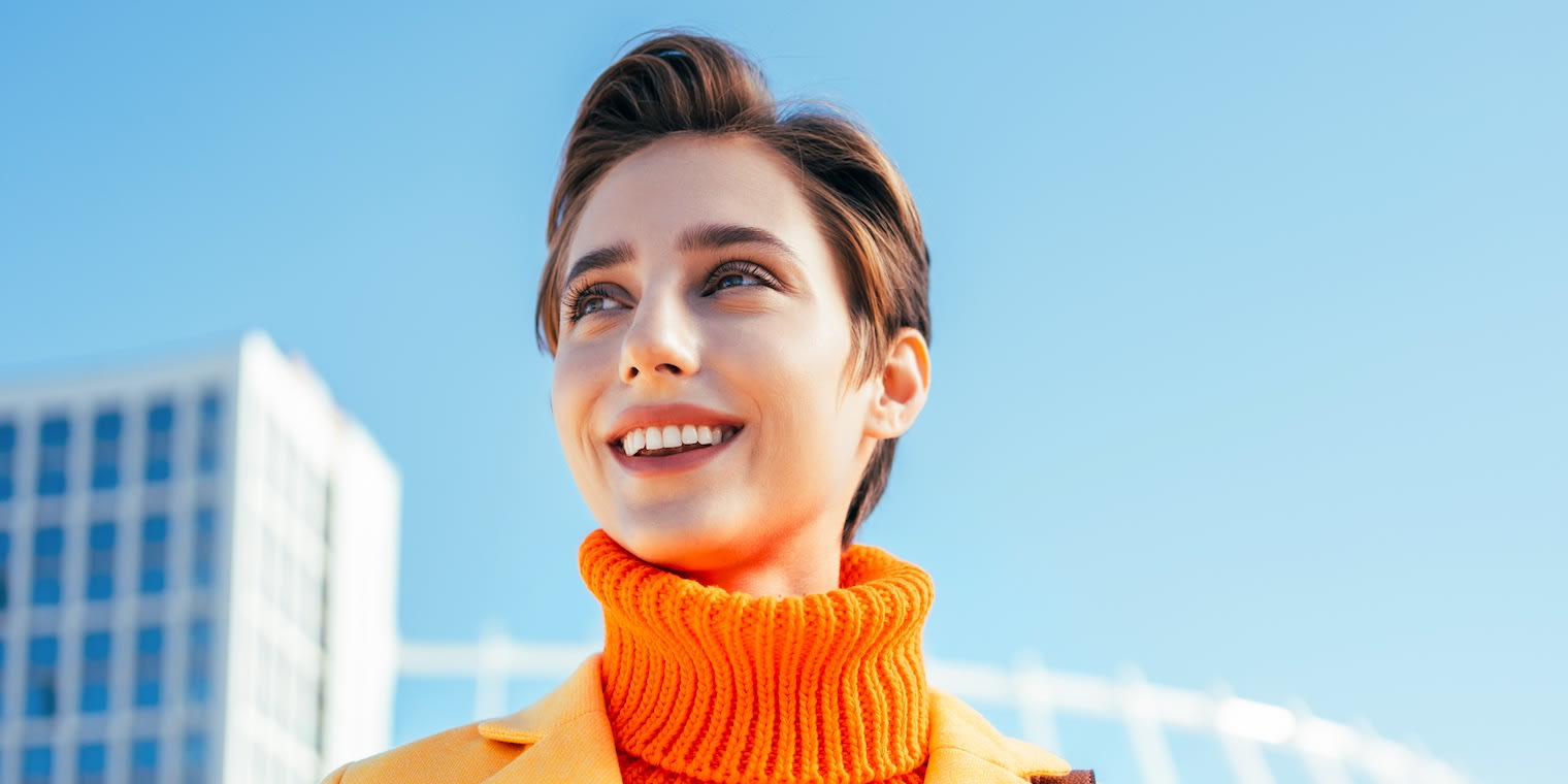 APCO Worldwide Case Study Hero Image: Smiling woman in an orange turtleneck sweater