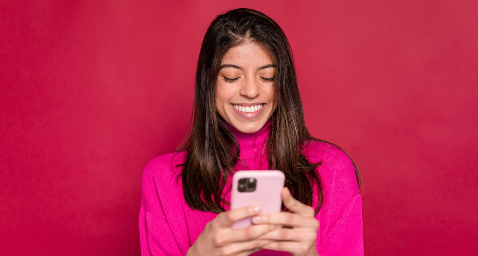 Business Travel Analytics Hero Image: Woman smiling and looking at her cell phone