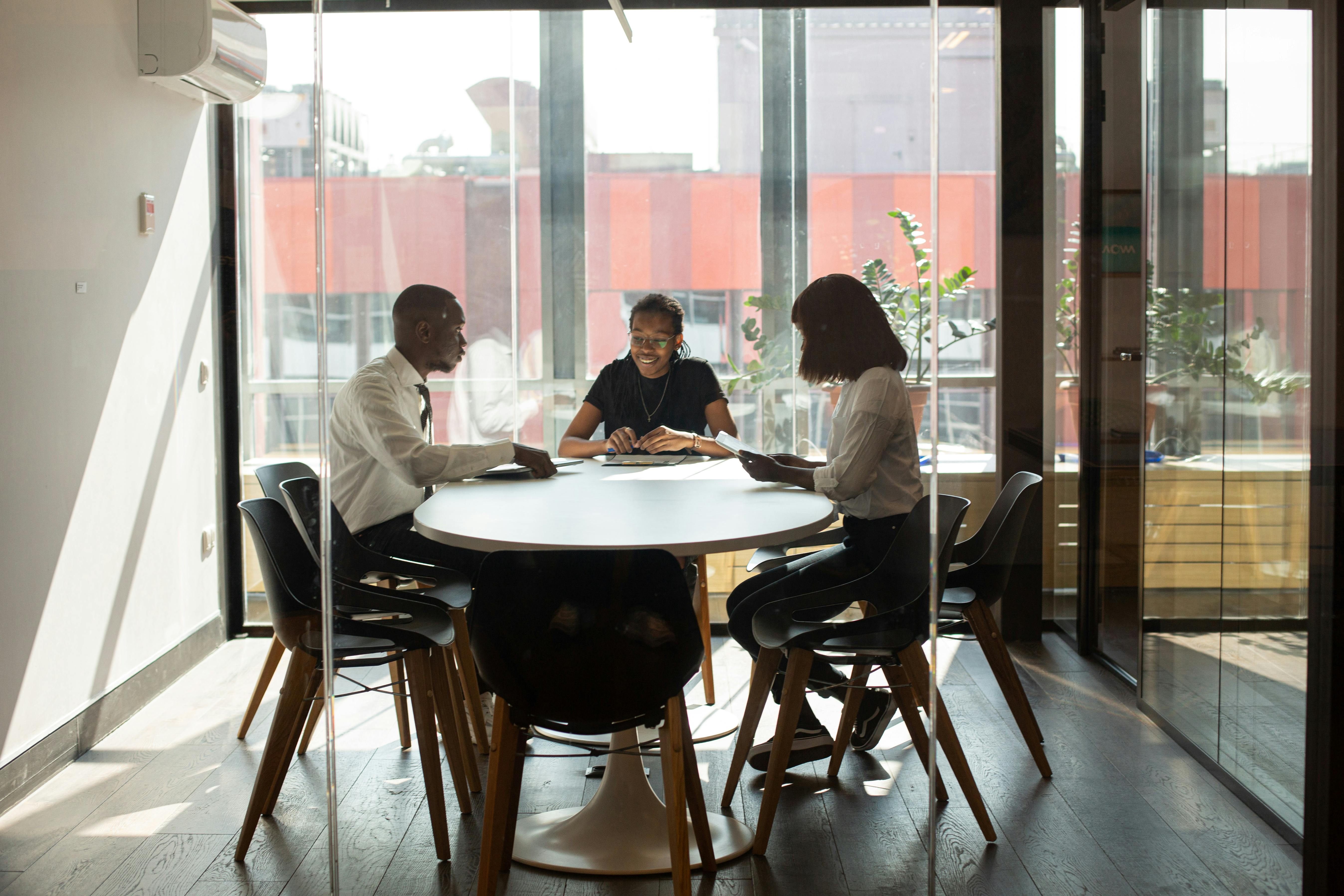 3 employés autour d'une table dans une pièce lumineuse d'un bureau