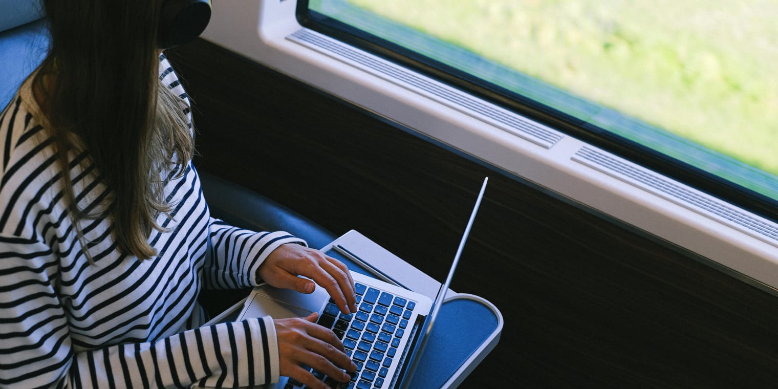 woman working on laptop while on a train. small business travel