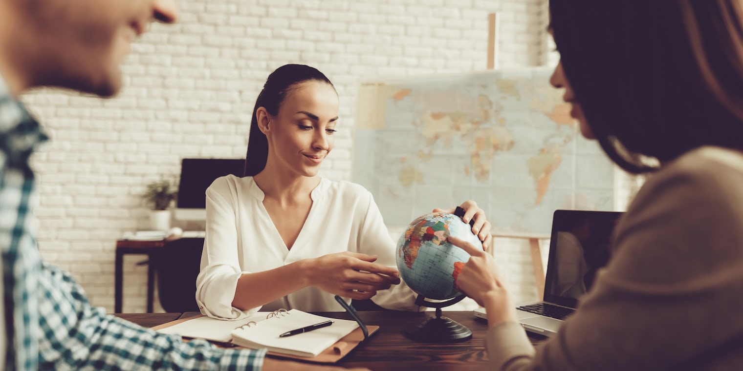 travel expense management woman looking at globe sitting with two people