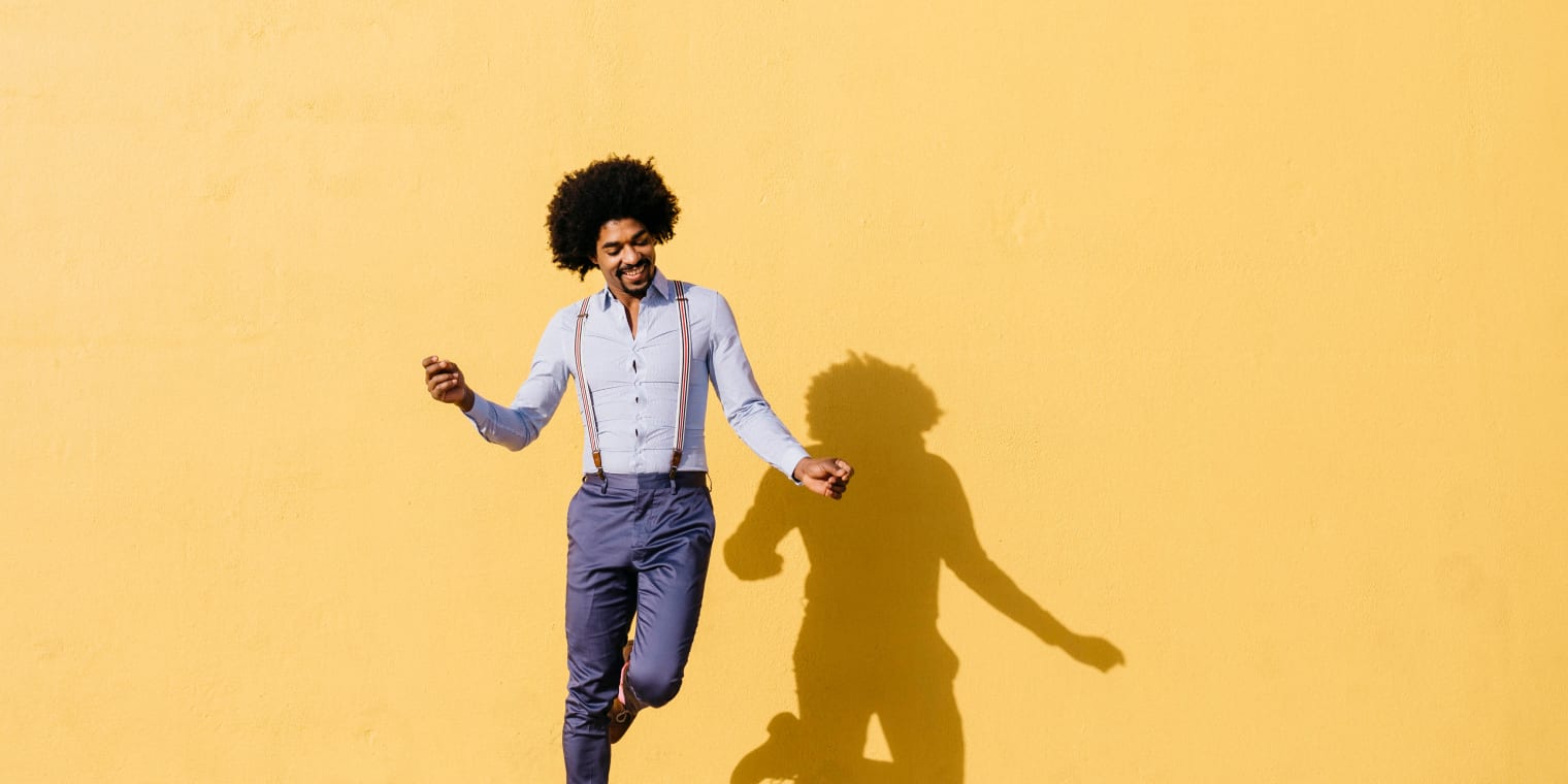 Man dancing in front of yellow background. Corporate expense management