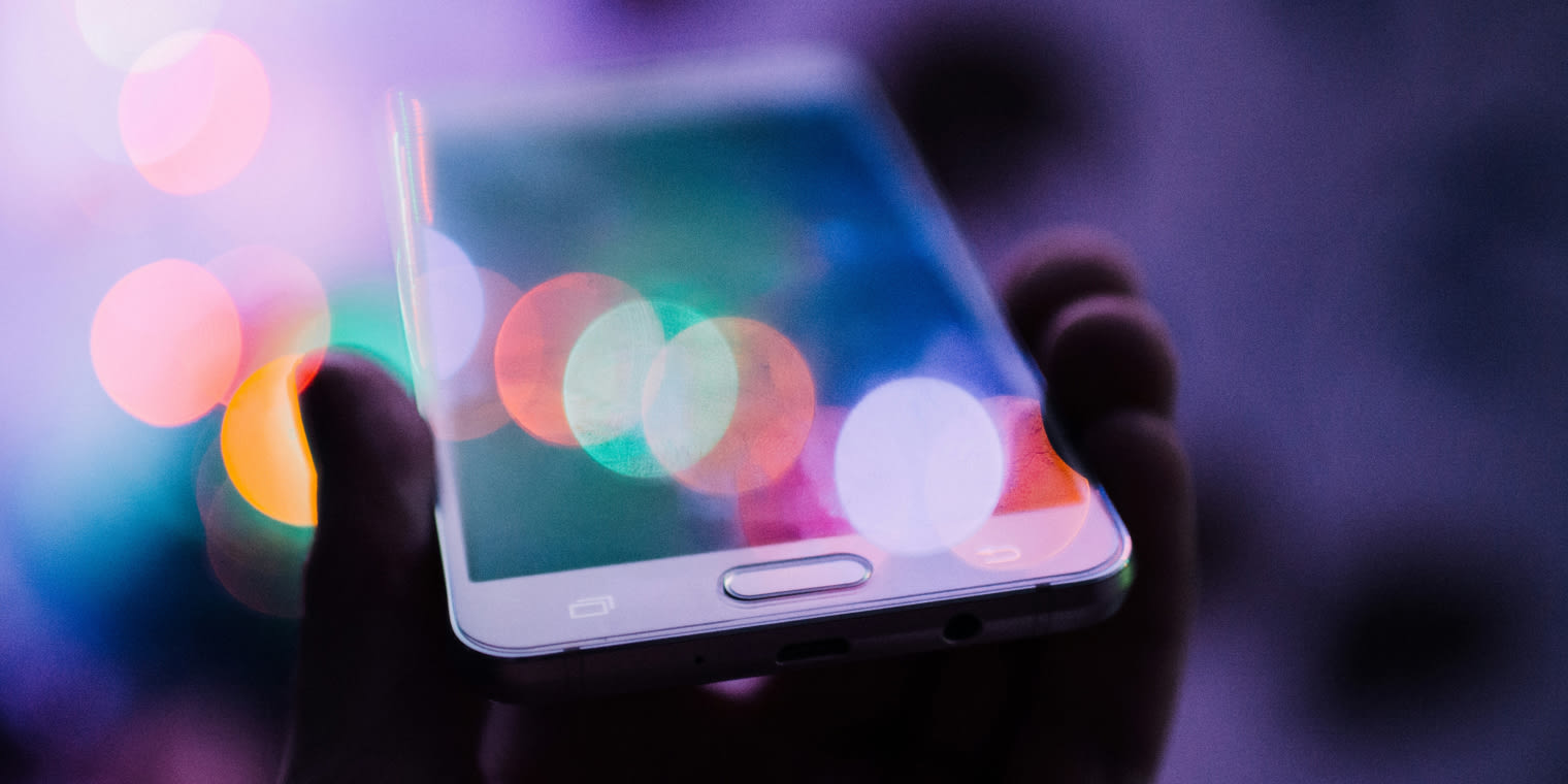Ein Smartphone mit unscharfen Lichtern im Hintergrund, das die Nutzung digitaler Reisemanagement-Tools zeigt.
