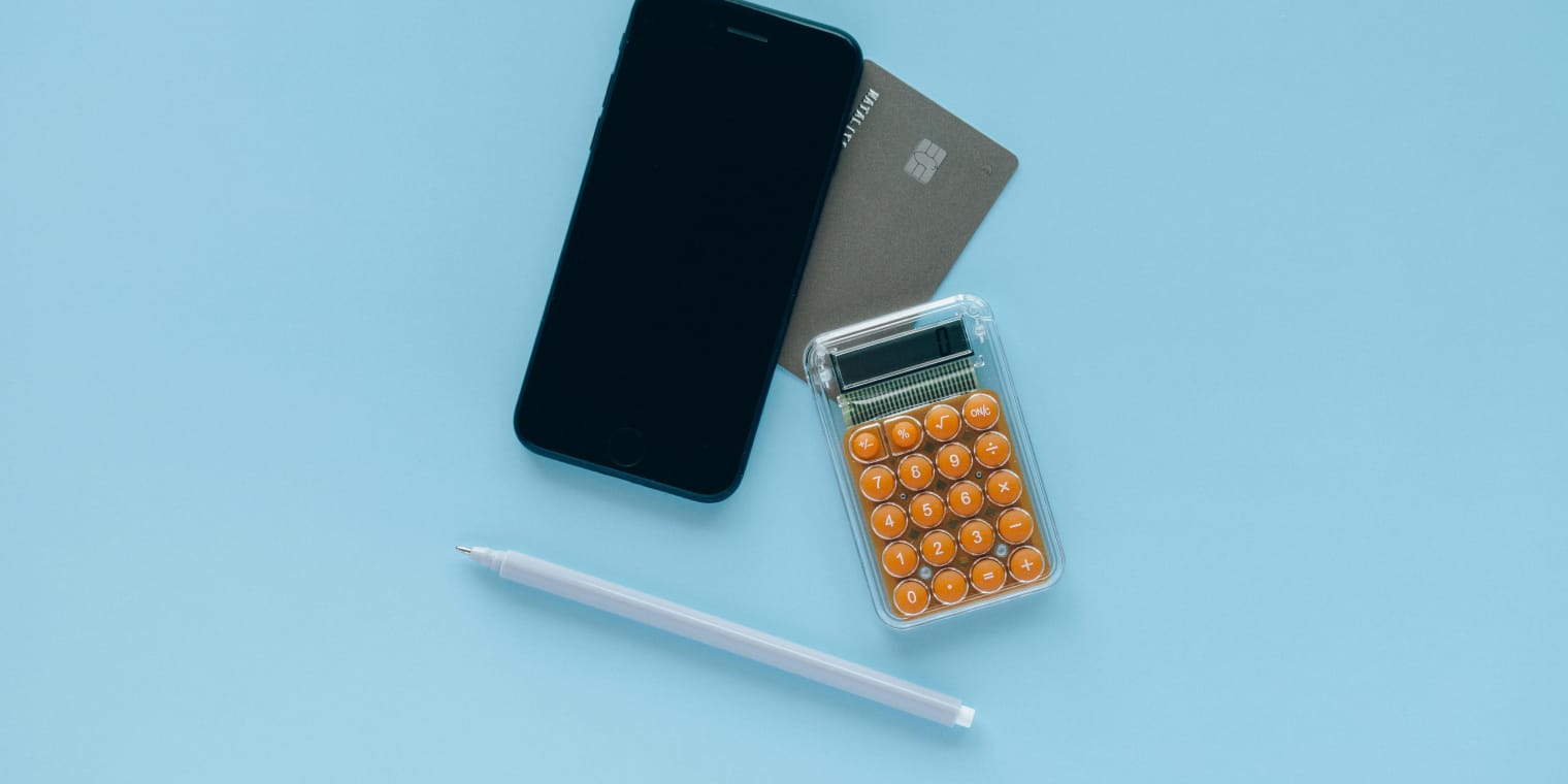 Calculator, phone and credit card on blue background. How to calculate per diem. 