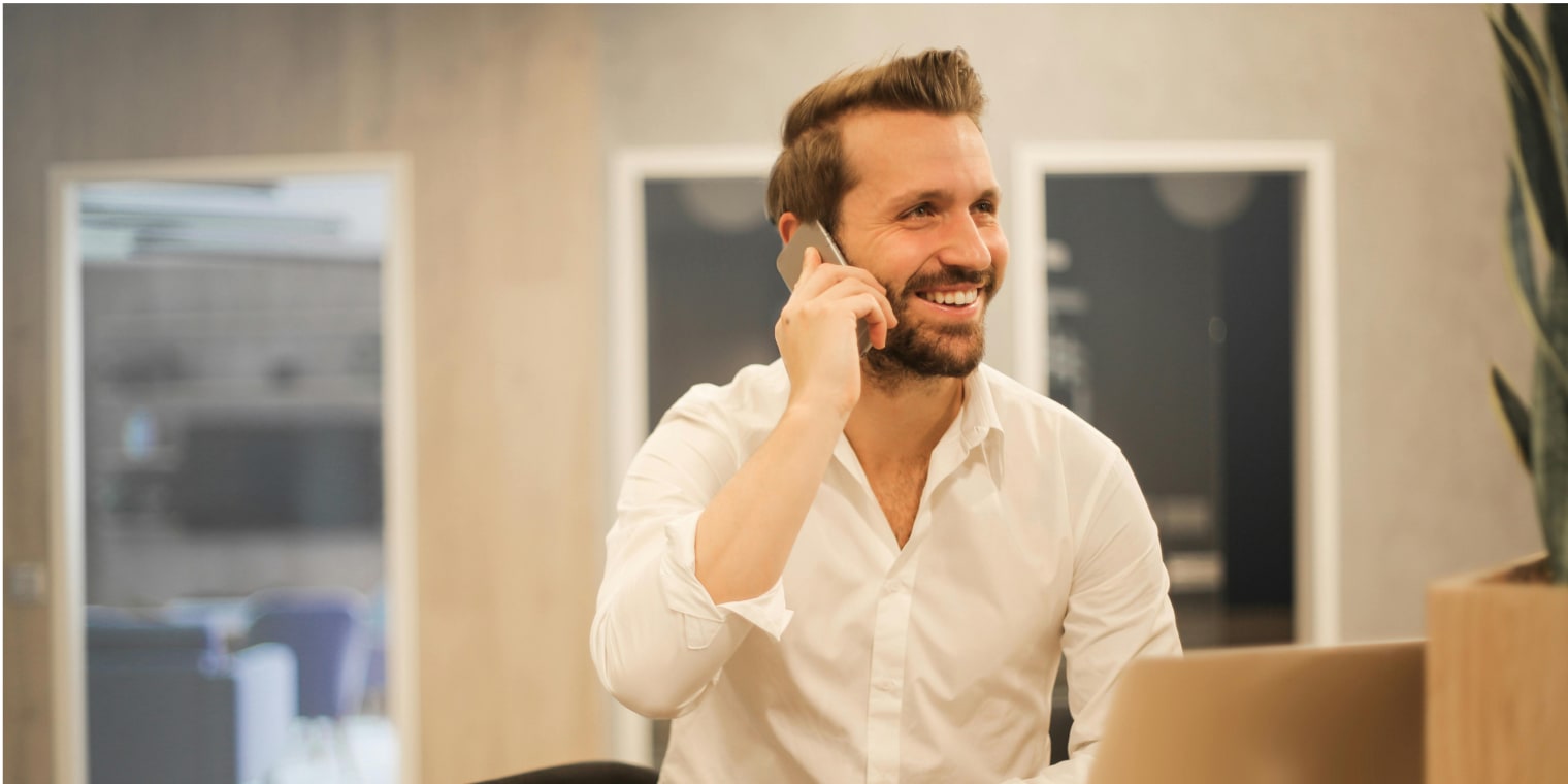 Ein Reisemanager im weißen Hemd, der mit einem Geschäftsreisekunden telefoniert.
