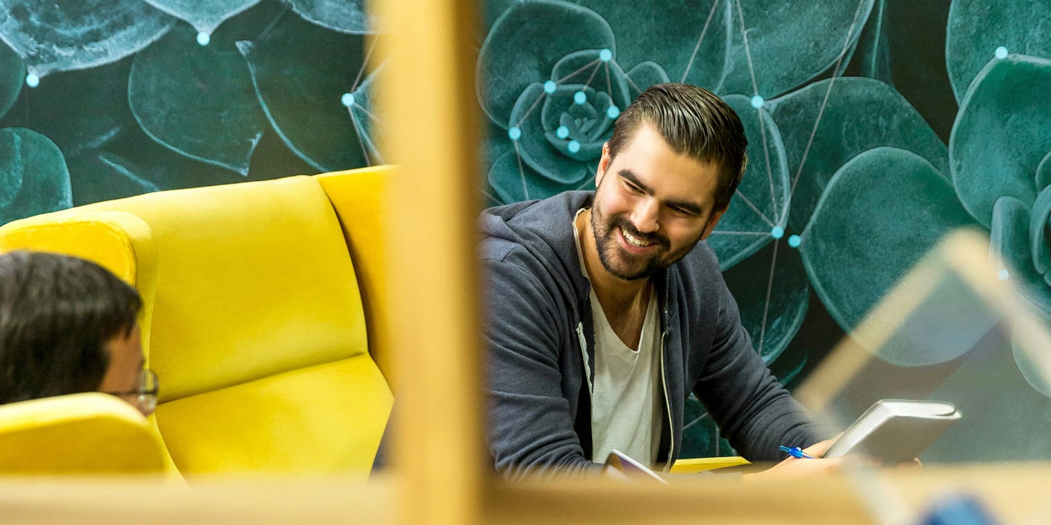 Zwei Personen unterhalten sich entspannt in einem modernen Büroraum über Reisemanagement für kleine und mittlere Unternehmen.