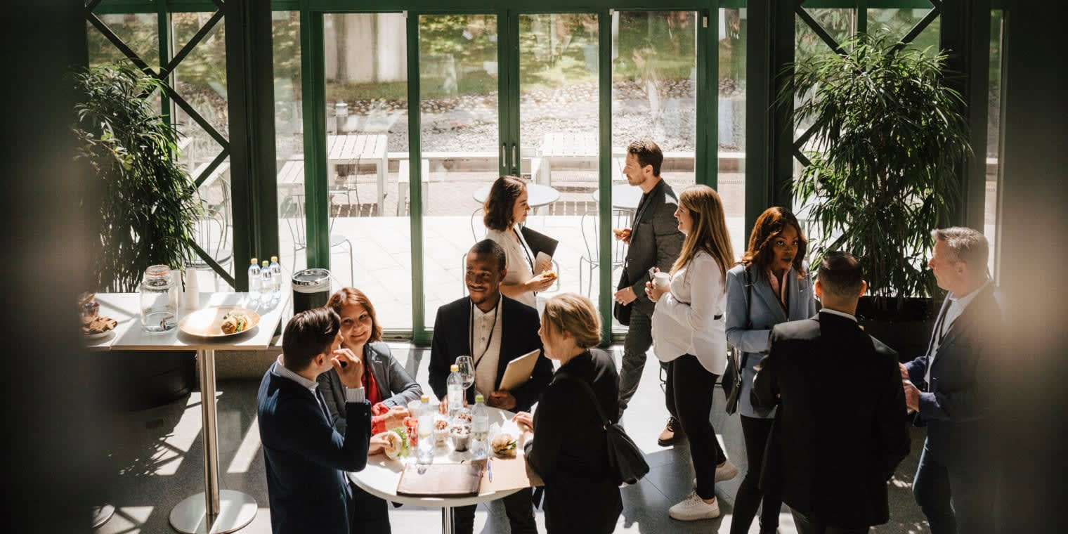 Eine Gruppe Geschäftsreisender unterhält sich im Sommer bei einer Messe darüber, was eine Geschäftsreise ist. 