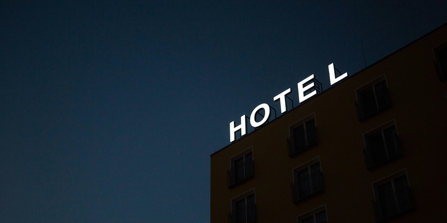 Ein Geschäftsreise Hotel bei Nacht mit leuchtenden Hotel-Buchstaben.