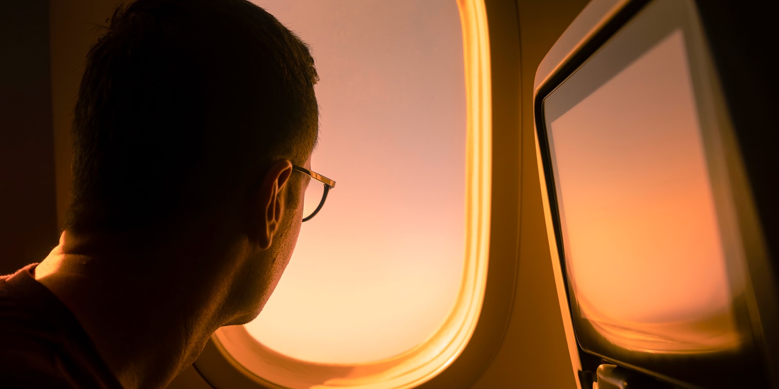 Silhouette of man looking out of a plane window at sunset. Navan Reddit Reviews