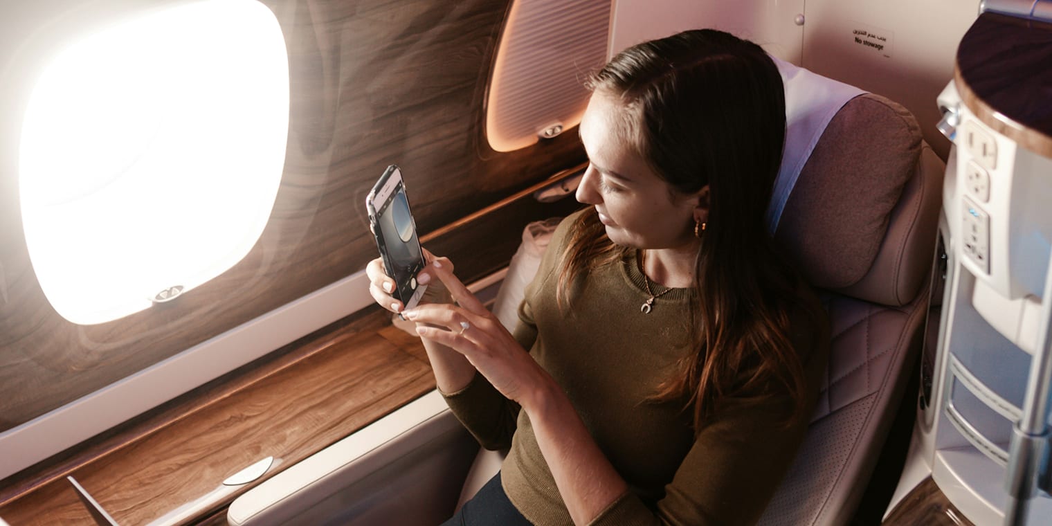 Eine braunhaarige Frau freut sich First Class Fliegen zu können.