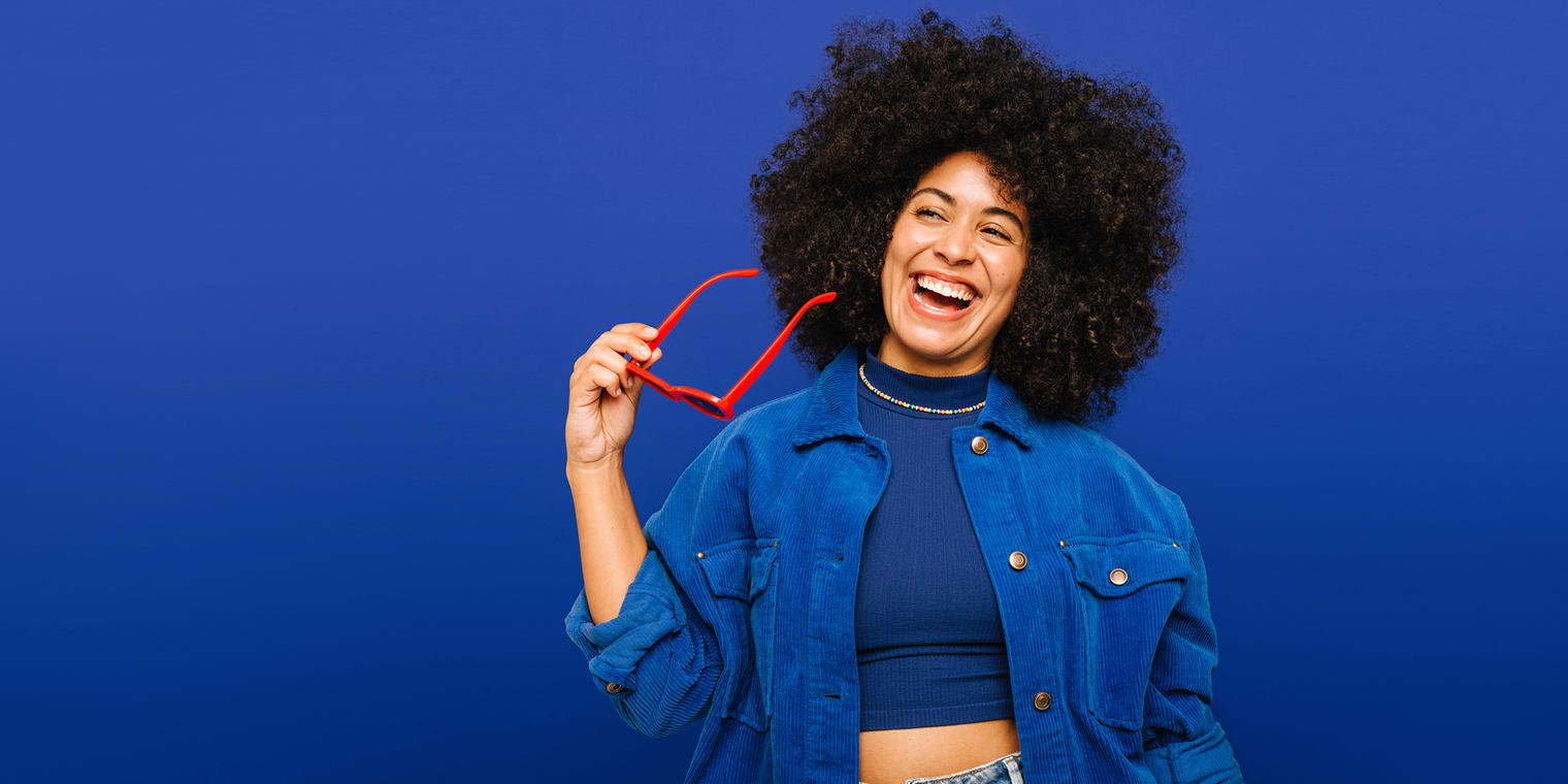 Woman smiling while holding red sunglasses. Navan reviews by EAs