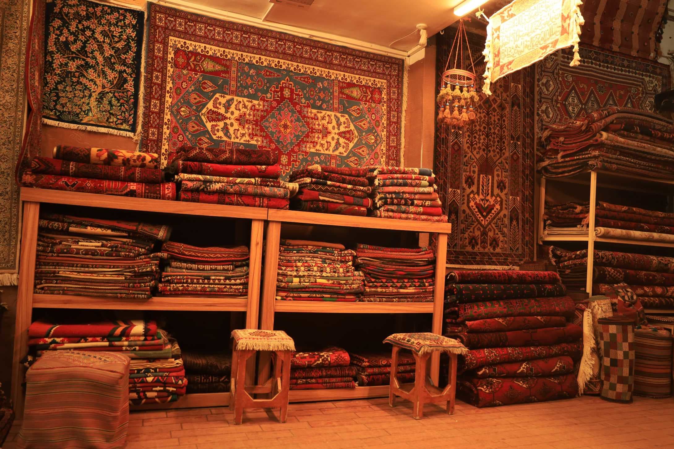 Hand-knotted Persian silk and wool rugs displayed in an Iranian carpet bazaar