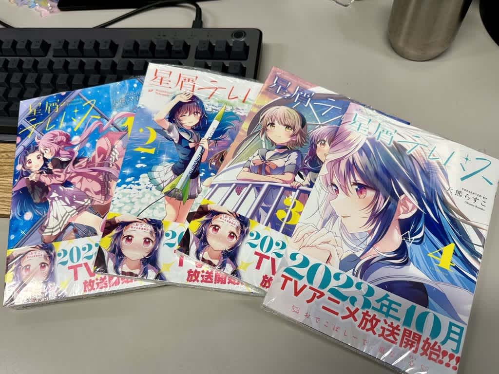 机の上に並べられた「星屑テレパス」1～4巻の漫画表紙。