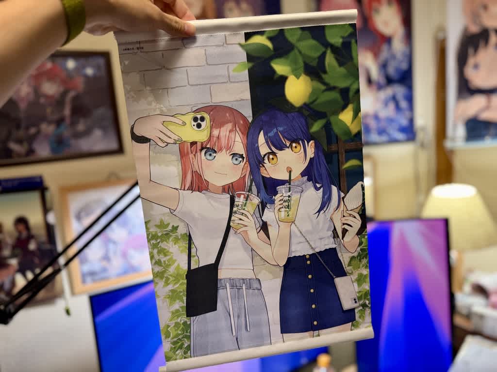 高山萌と吉岡るるがレモネードを飲みながら自撮りをしているイラストのタペストリー