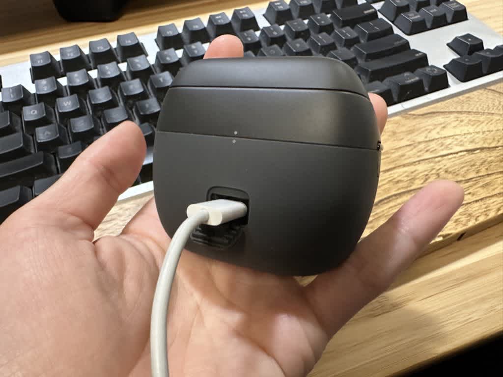 手のひらに置かれた充電中の黒いデバイスとキーボード。