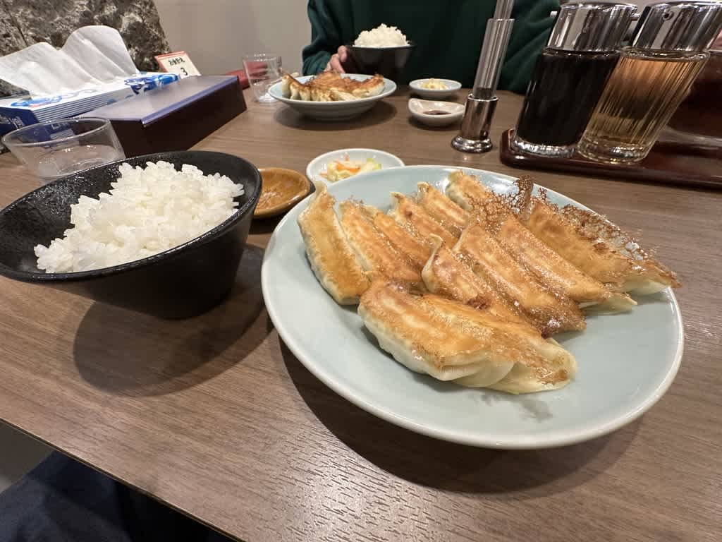 テーブルに餃子とご飯が並ぶ食事風景。