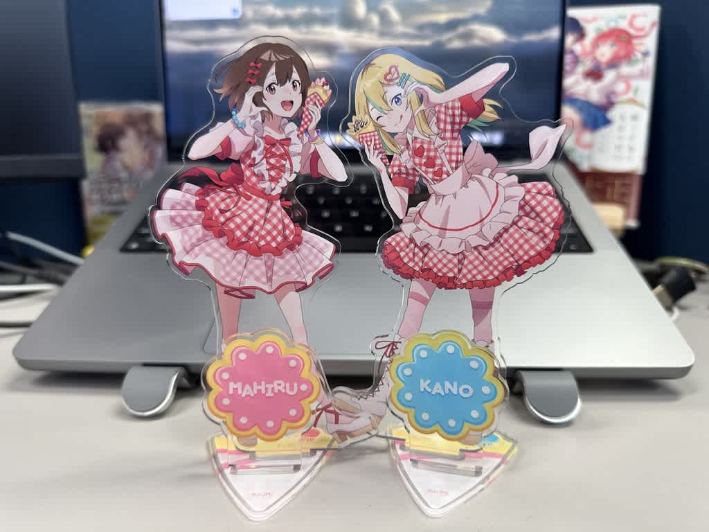 赤と白の衣装を着たキャラクターのアクリルスタンドが机の上に置かれている。
