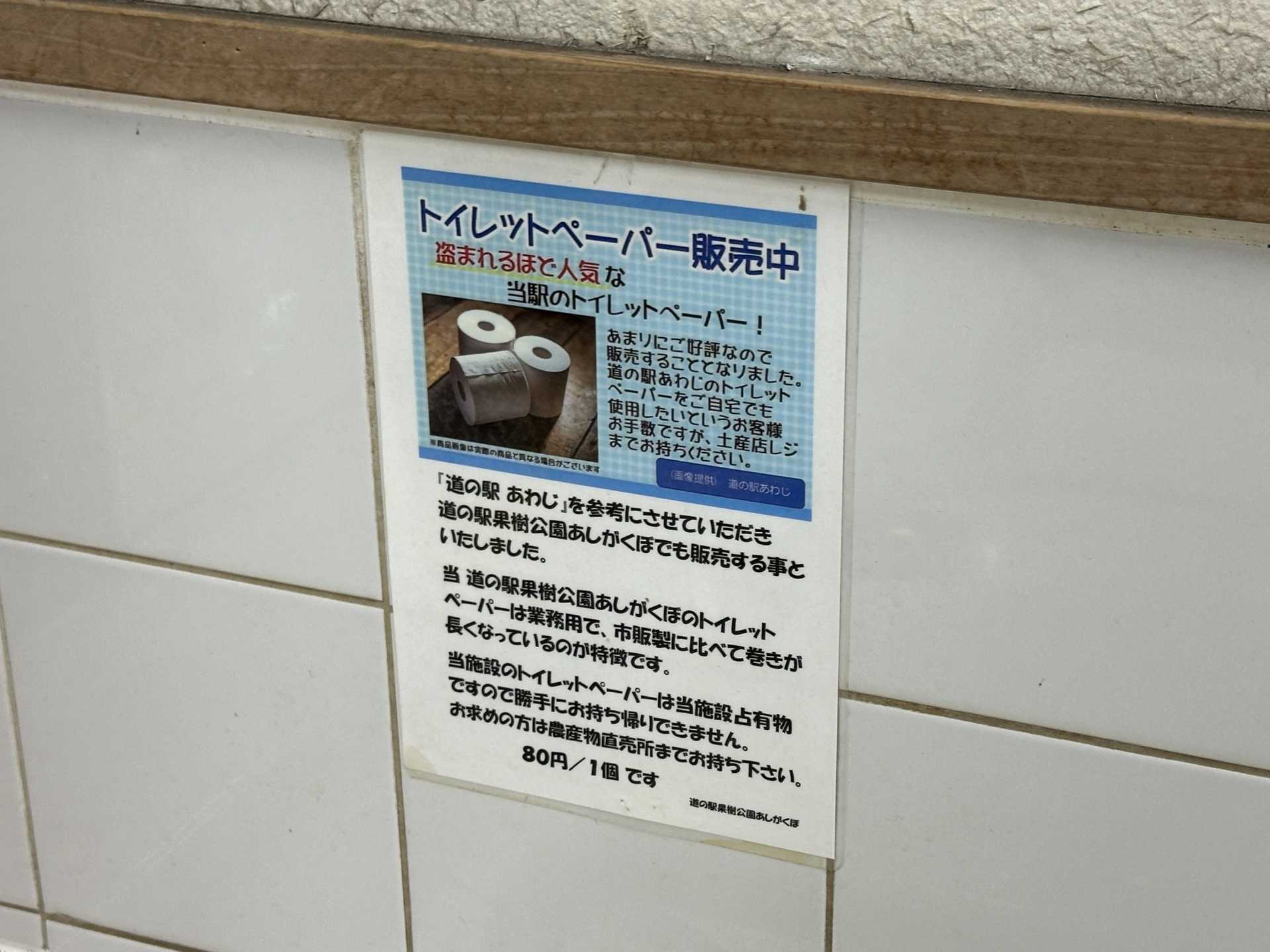 トイレに「トイレットペーパー販売中　盗まれるほど人気な当駅のトイレットペーパー！ 1個80円」と書かれた張り紙が貼られている