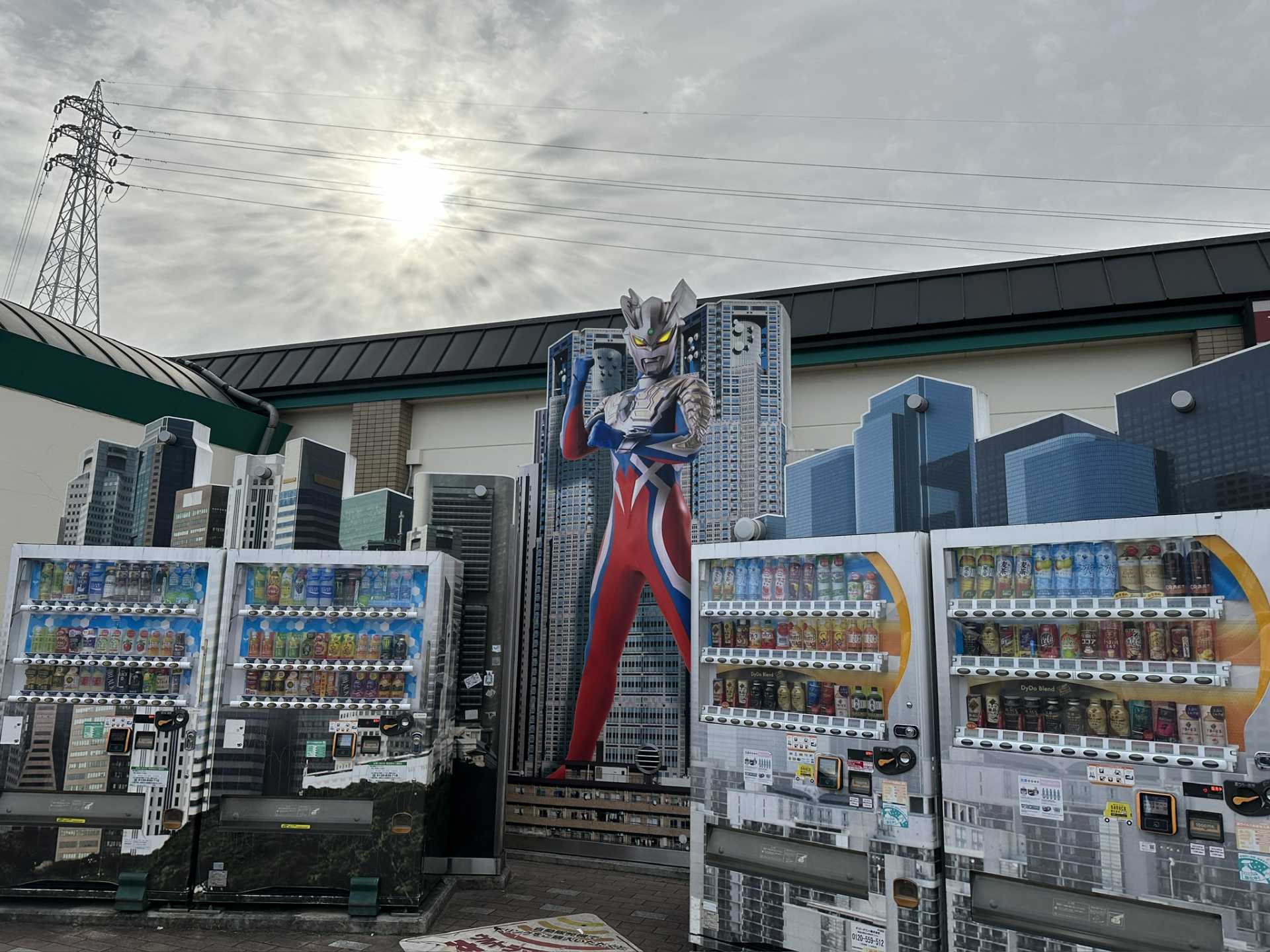 4台の自販機の裏に大きなウルトラマンのパネルが置かれている様子を撮影した写真