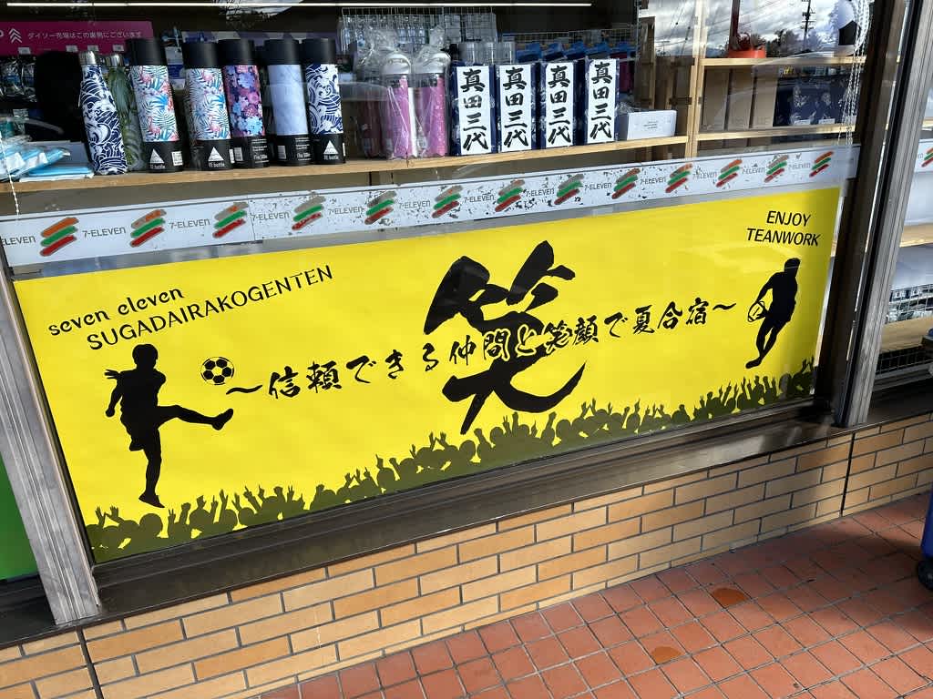 セブンイレブン菅平高原店の張り紙の写真。笑 〜信頼できる仲間と笑顔で夏合宿〜 と書かれている。