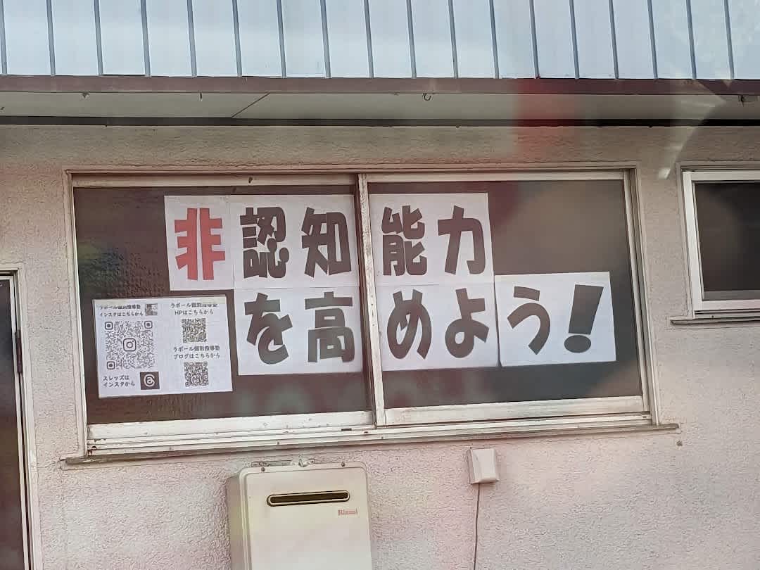 非認知能力を高めよう！とA4コピー用に1文字ずつ書かれた張り紙が塾の窓に貼られている