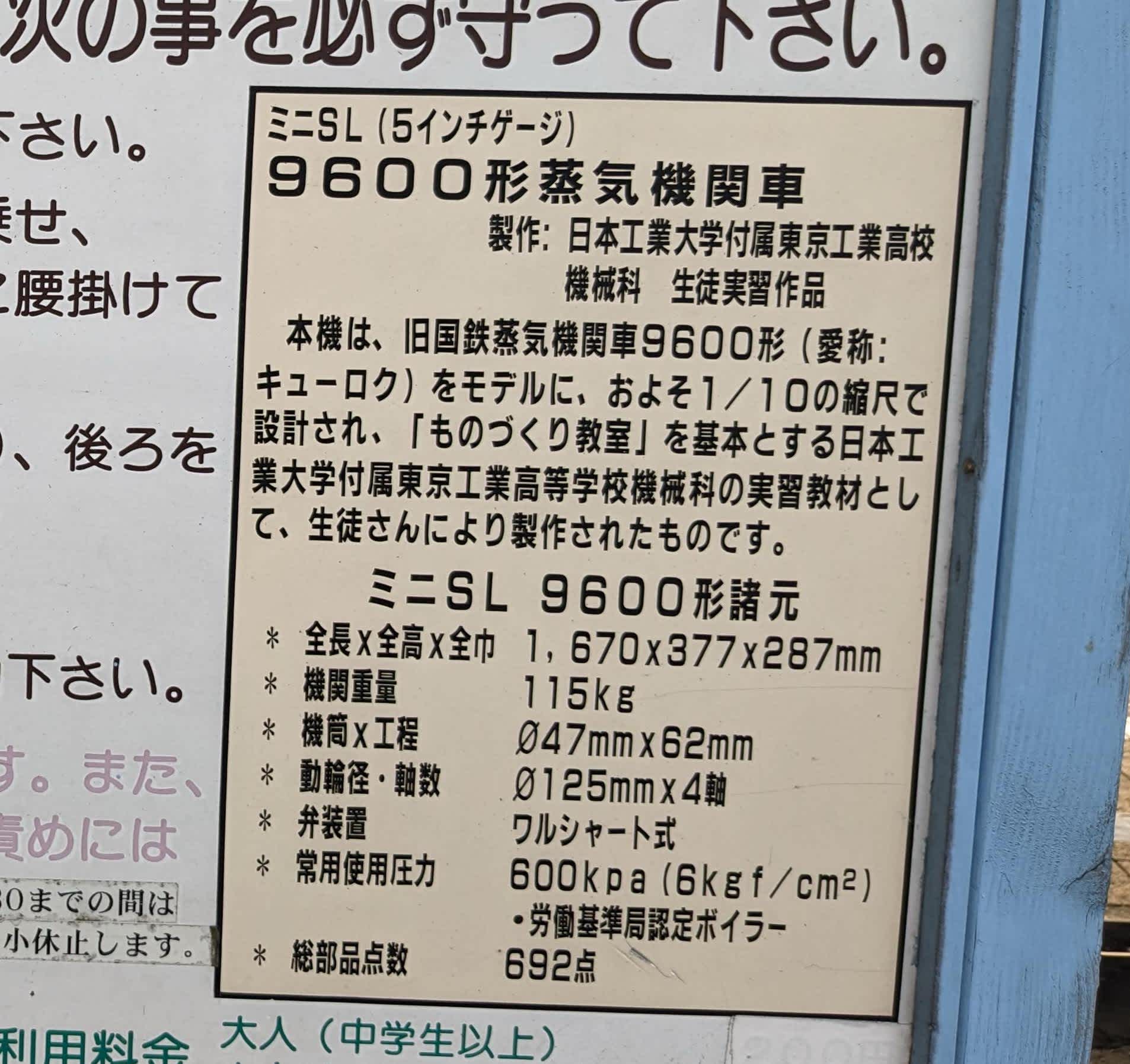 ミニSLの紹介のパネル。次のように書いてある: ミニSL（5インチゲージ）9600形蒸気機関車 製作：日本工業大学付属東京工業高校機械科 生徒実習作品 本機は、旧国鉄蒸気機関車9600形（愛称：キューロク）をモデルに、およそ1／10の縮尺で設計され、「ものづくり教室」を基本とする日本工業大学付属東京工業高等学校機械科の実習教材として、生徒さんにより製作されたものです。