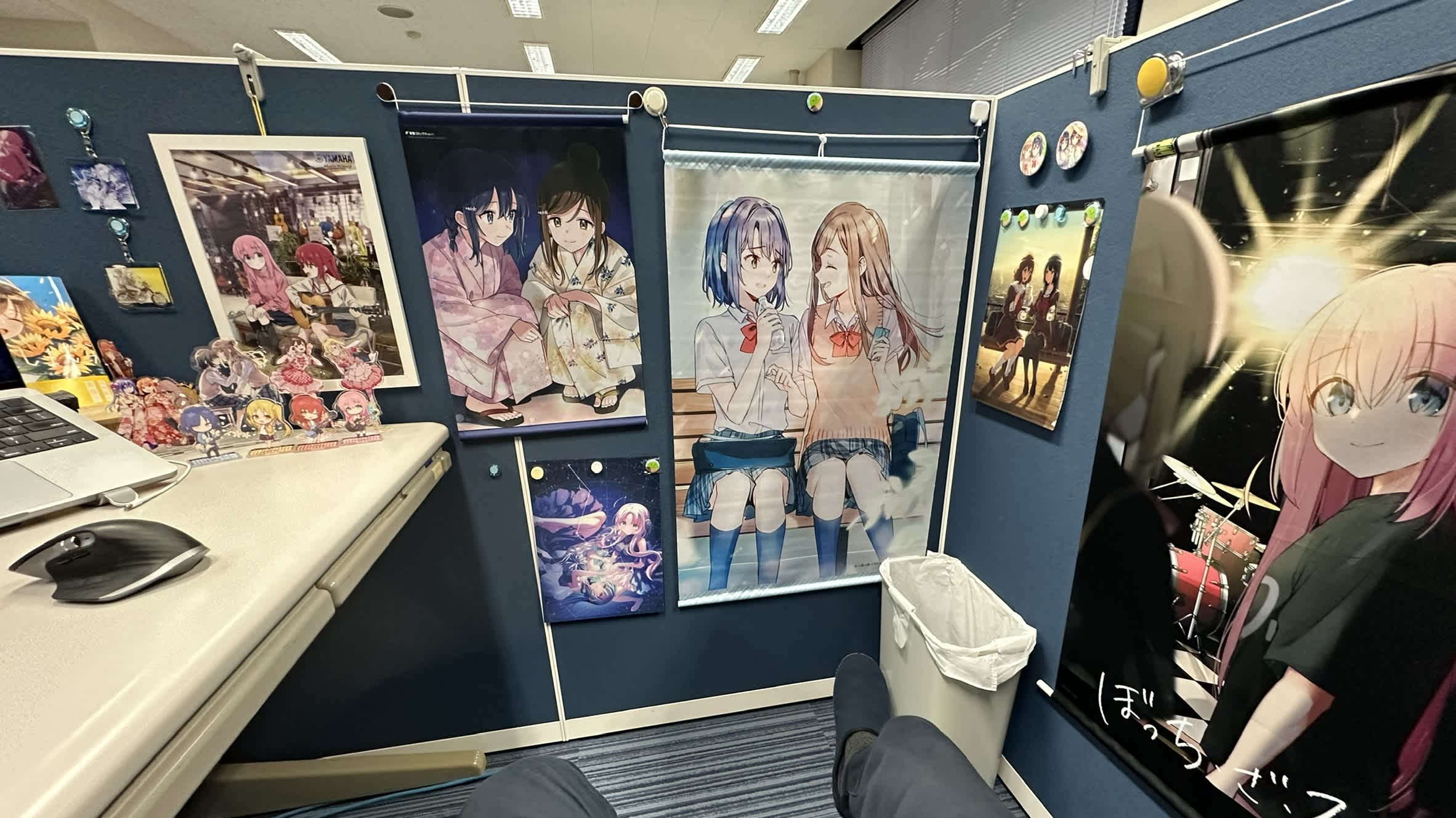 安達としまむらのタペストリーやフィギュアが飾られたデスク。