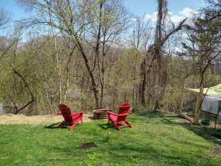 Lower backyard with peaceful wooded view on side of hill. Two chairs and fire pit.