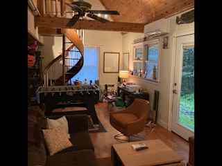 Living room with foosball table and gorgeous spiral staircase that leads to the master bedroom. Spectacular view of the woods outside the living room.