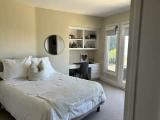 Sitters bedroom with en suite bathroom shower+tub and French doors leading out to balcony