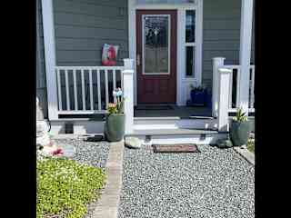 Entry with covered porch and wicker chairs.