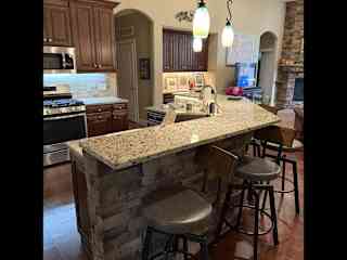 Kitchen counter and bar area with four bar stools.