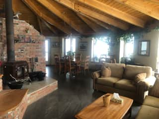 The living room with lots of comfy couches and a wood stove/fireplace. The dining room sits beyond that next to the kitchen. The space has lots of windows for lots of light and great views.