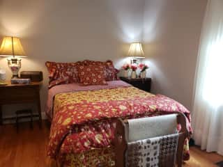 Guest bedroom with full size bed, 2 nightstands, smart TV, small chest of drawers.