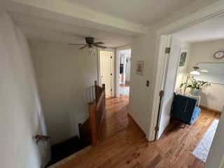 View from guest room doorway, with office, main bedroom, bathroom doors visible, and staircase down to the living room