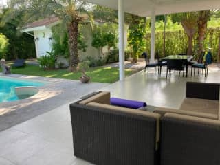 The covered terrace by the pool with sofas and dining table.