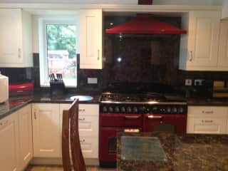 Our kitchen, it has a range with a 5 ring gas hob and two ovens. On the other wall, there is another oven AEG, built in, and we use that for baking cakes! There's an island in the middle, lots of cupboard space. A dishwasher