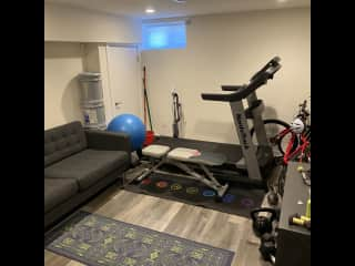 Basement gym area with sofa and tv (unfortunately our treadmill is no longer with us we have a lot of dumbbells, kettlebells, bands, weighted vest.)