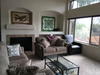 The living room has vaulted ceilings and large windows on two of three walls