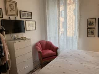 Bedroom with tv on wall above dresser. There will be empty dresser drawers available and a clothing rack to hang clothes