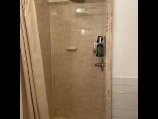 Rain shower head walk-in shower supplied with shampoo, conditioner, body wash and soap.