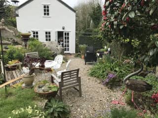 Patio area to kitchen side of cottage. 
Another patio area at the back of the cottage and garden swing catching the last of the sun beyond this.