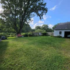 The large backyard and detached garage with picnic table and archery setup