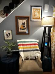 A sitting chair. This is the one you'll move for sweeping/litter box duties. Art by Blackfeet ledger artist John Isaiah Pepion. Laundry is in a cubby behind the yellow quilt which you can see hanging in the right of this photo.