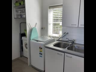 Large laundry off kitchen with top loader washing machine, dryer and double sink.