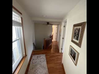 View from guest room doorway, with office, main bedroom, bathroom doors visible, and staircase down to the living room