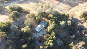 Our homestead is five acres with the studio apartment over the detached garage and main home with wrap around porch surrounded by our oak woodlands.