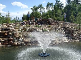 Large ornamental pond to the south of the house with waterfalls and a fountain. There is a fire firepit near it as well as a big kid's play structure, sandbox and playhouse.