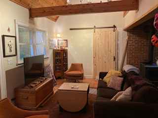 Living room with barn door that leads into the addition under construction. Wood burning stove just visible to the right.