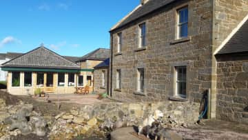 Rosie and Tilly on front of the west side of the house shwing the garden room and fledgling garden